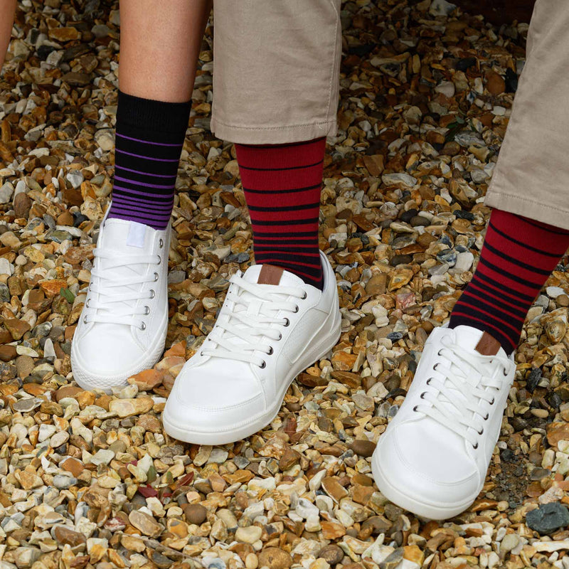 Man sitting on bench wearing Peper Harow burgundy Retro Stripe men's luxury socks