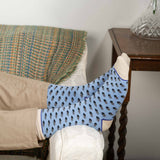 Man laying on sofa wearing tan trousers and sky Disruption men's luxury socks from Peper Harow