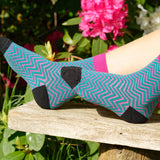 Woman sitting outside on a bench wearing teal Zigzag women's luxury socks by Peper Harow